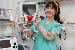 Das Bild zeigte ein Fachkraft die ein Gummi Herz zwischen einem Defibrillator hält 