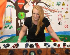 Das Bild zeigt eine Frau beim Kicker spielen