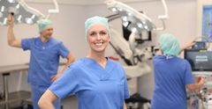 Eine Frau im blaue Krankenpflegekittel mit Technischer Ausrüstung im Hintergrund