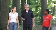 Das Bild zeigt zwei Frauen und ein Mann, die zusammen spazieren