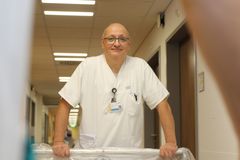 Das Bild zeigt ein Pflegefachmann der ein Krankenbett schiebt 