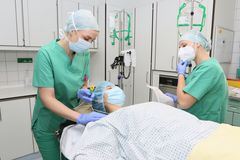 Das Bild zeigt zwei Fachkräfte und eine Patientin im OP