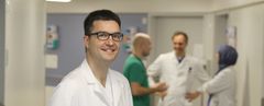 Das Bild zeigt ein Arzt im Vordergrund und Mitarbeiter im Hintergrund