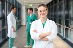 Das Bild zeigt eine Ärztin im Vordergrund und zwei Ärzte im Hintergrund