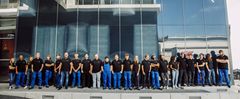 Gruppe junger Menschen in Arbeitskleidung und Freizeitkleidung vor einem modernen Gebäude, stellvertretend für Ausbildungs- und Studienmöglichkeiten bei GRIESHABER Logistik.