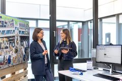 Zwei Mitarbeitende im Gespräch in einem modernen Büro mit Infowand und Monitor – zeigt die offene Unternehmenskultur von GRIESHABER.