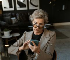 Eine ältere Dame schaut sich auf dem Smartphone offene Stellen einer Steuerkanzlei an.