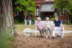 Zwei Bewohnerinnen des ServiceWohnen und ein Pflegender sitzen auf der Bank