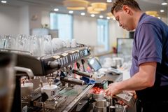 Ein Mitarbeiter unseres inklusiven Arbeitsbereichs fairDienst arbeitet an der Kaffeemaschine.