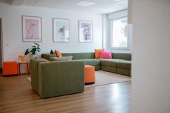 Schön eingerichteter Arbeitsbereich mit Couch und bunten Bildern.
