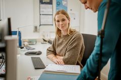 Ein neuer Kollege unterschreibt seinen Arbeitsvertrag bei einer Mitarbeiterin der Kaiserswerther Diakonie.