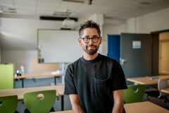 Ein Lehrer aus der Familienakademie steht im Klassenraum und lächelt.