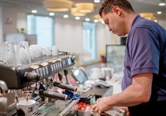Ein Mitarbeiter der fairDienst arbeitet an der Kaffeemaschine.