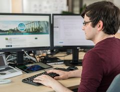 KOMSA-Mitarbeiter am modern ausgestatteten Arbeitsplatz mit zwei Monitoren
