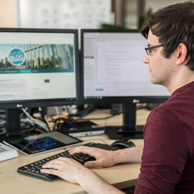 KOMSA-Mitarbeiter am modern ausgestatteten Arbeitsplatz mit zwei Monitoren