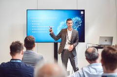 KOMSA Mitarbeiter steht am Flatscreen und hält Präsentation