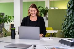 Mitarbeiterin der KOMSA steht am Arbeitsplatz und arbeitet am Laptop