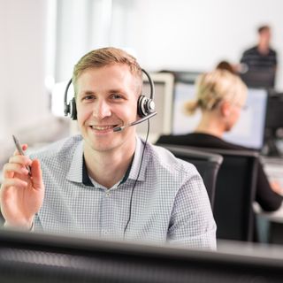 Mitarbeiter der KOMSA trägt ein Headset und berät einen Kunden telefonisch