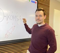 Auszubildender bei KOMSA sitzt mit Tablet am Arbeitsplatz 