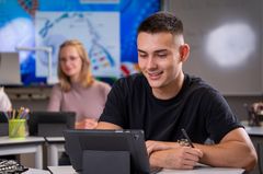 Auszubildender bei KOMSA sitzt mit Tablet am Arbeitsplatz 