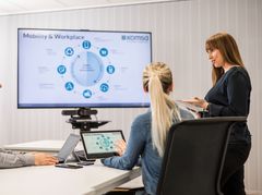 Zwei Mitarbeiterinnen besprechen sich und arbeiten mit Tablet und Monitor