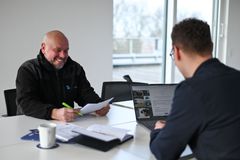 Ein Produktionsmitarbeiter in der Produktionshalle hält ein Karosserieteil mit Arbeitshandschuhen in der Hand.