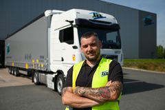 Ein Produktionsmitarbeiter in Warnweste in der Produktionshalle bedient die Montagestation