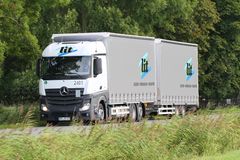 L.I.T. Mitarbeiter mit Warnweste lehnt lächelnd vor einem weißen LKW auf dem Firmengelände.