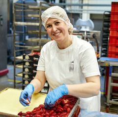 Mitarbeiterin belegt Kuchen mit Erdbeeren