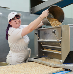 Fachkraft für Lebensmitteltechnik befüllt Maschine