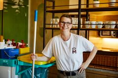 Reinigungskraft mit Wischmopp und Wagen