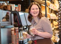 Auszubildende steht lachend an der Kaffeemaschine