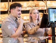 Praktikant und Verkäuferin bedienen gemeinsam die Kasse