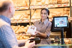 Auszubildende bedient einen Kunden an der Bäckertheke