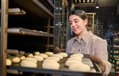 Auszubildende schiebt Teiglinge in den Ofen