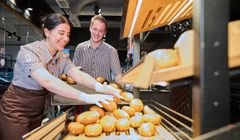 2 Azubis sortieren Brötchen in der Auslage ein