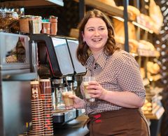 junge Frau bereitet Kaffee an einer Kaffeemaschine zu 