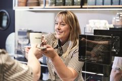 Verkäuferin reicht einen Kaffee über die Theke
