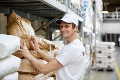 Mann nimmt Mehlsack aus dem Lager einer Bäckerei