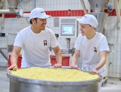 zwei junge Männer schieben einen großen Kessel mit Früchten
