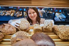 Verkäuferin räumt Brot ins Backwarenregal ein