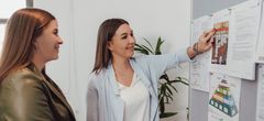 Zwei Mitarbeiterinnen an einer Pinnwand