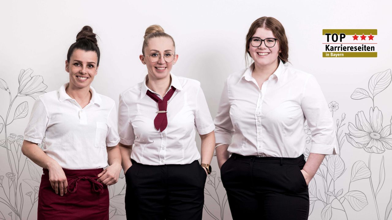 Drei Frauen aus dem Bereich Service stehen nebeneinander und blicken lächelnd in die Kamera. Auf dem Bild steht mittig in weißer Schrift #getinwolfed.