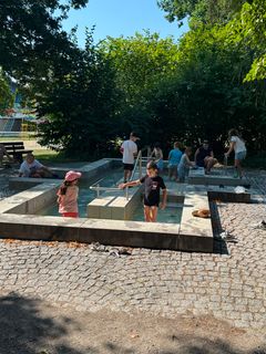 Kinder spielen draußen in Wasseranlage.