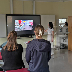 Eine Pflegerin und ein Therapeut sehen sich auf dem Gang gemeinsam eine Patientenakte an.