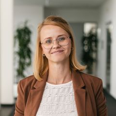 Eine junge Frau in weißer Bluse und braunem Blazer präsentiert sich als Recruiterin der ProPotsdam GmbH.