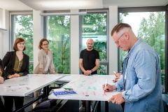 Mitarbeiter*innen der ProPotsdam beim Brainstorming in einem modernen Konferenzraum mit beschreibbaren Tischen