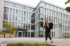 eine junge Frau läuft auf das moderne Bürogebäude der ProPotsdam zu