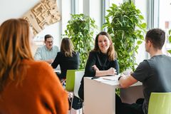 Mehrere Menschen sitzen in einem Pausenbereich zusammen und unterhalten sich,
