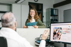 Eine junge Frau steht am Bürotresen und unterhält sich mit einem Kollegen